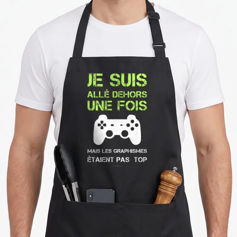 Tablier de cuisine noir avec texte vert Je suis allé dehors une fois et une manette de jeu vidéo blanche en dessous.