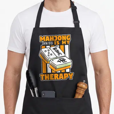 Tablier de cuisine noir avec illustration de tuiles de Mahjong et texte orange MAHJONG IS MY THERAPY.