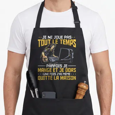 Tablier de cuisine noir avec illustration d'un gamer au clavier et texte humoristique en jaune et blanc.