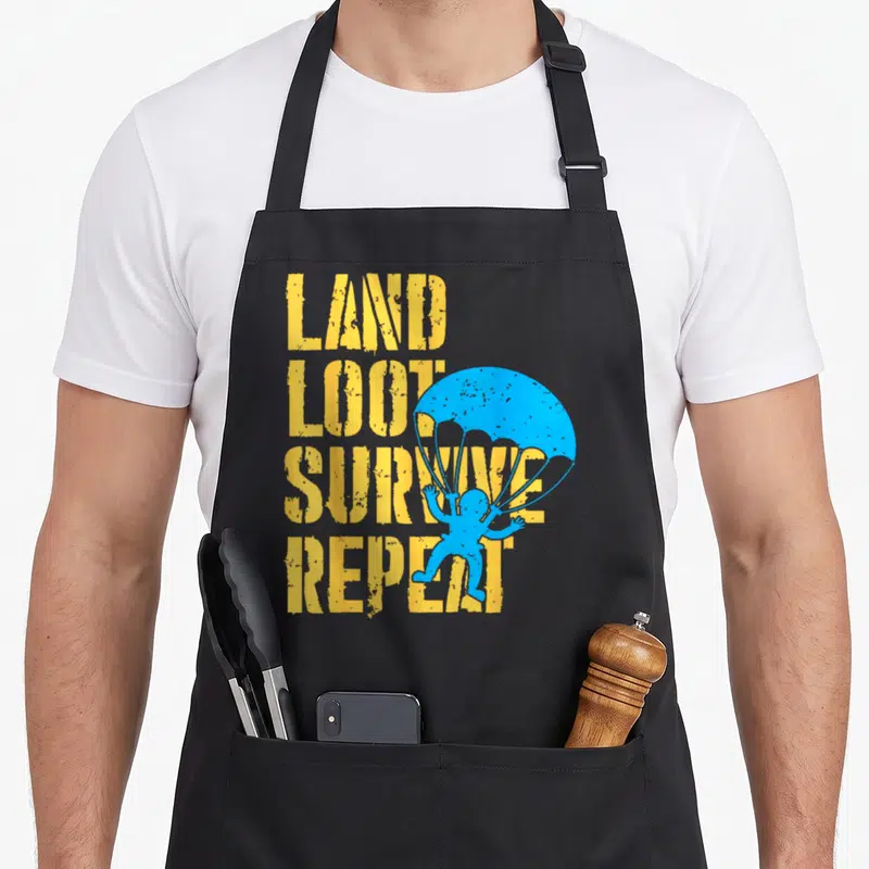 Tablier de cuisine noir avec texte Land Loot Survive Repeat et silhouette parachutiste bleue.