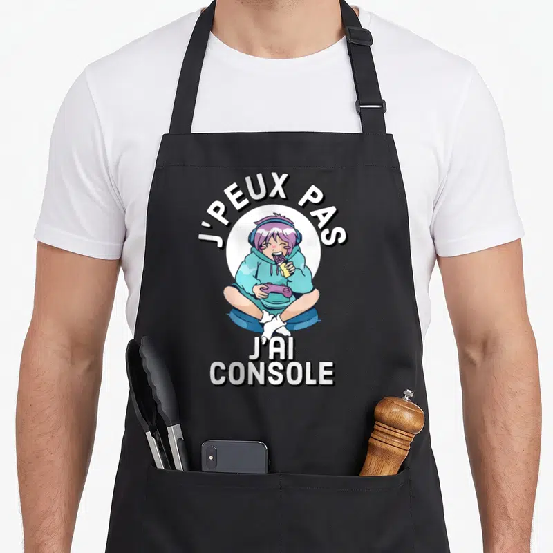 Tablier de cuisine noir avec un personnage anime aux cheveux violets tenant une manette et des chips.