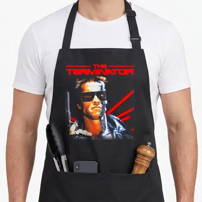 Tablier de cuisine noir avec illustration du Terminator et texte rouge en haut.