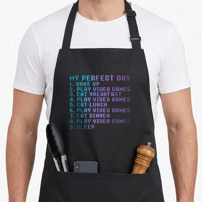 Tablier de cuisine noir avec une liste textuelle colorée My Perfect Day et Play Video Games en style pixel art.