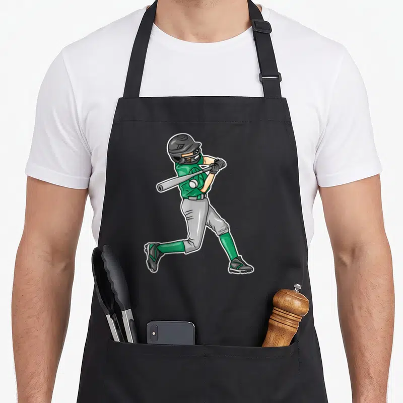 Tablier de cuisine noir avec illustration d'un joueur de baseball en tenue verte et casque noir en train de frapper la balle.
