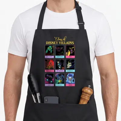 Tablier de cuisine noir avec illustration Class of Disney Villains Yearbook montrant neuf personnages maléfiques sur fond coloré.