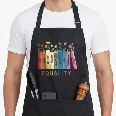 Tablier de cuisine noir avec une rangée de livres colorés fleurissant et le mot égalité en bas.
