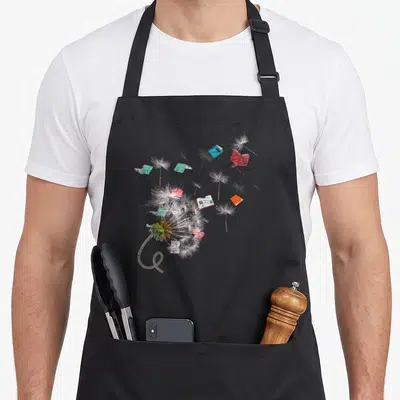 Tablier de cuisine noir avec illustration d'un pissenlit dont les graines deviennent des livres ouverts multicolores.