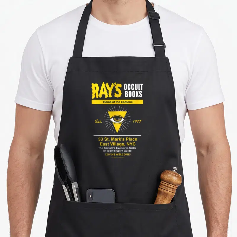 Tablier de cuisine noir avec le logo jaune Ray's Occult Books et un œil stylisé au centre.