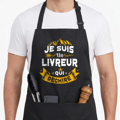 Tablier de cuisine noir avec inscription Je Suis Un Livreur Qui Déchire en blanc et jaune, orné de montagnes et d'une bannière.