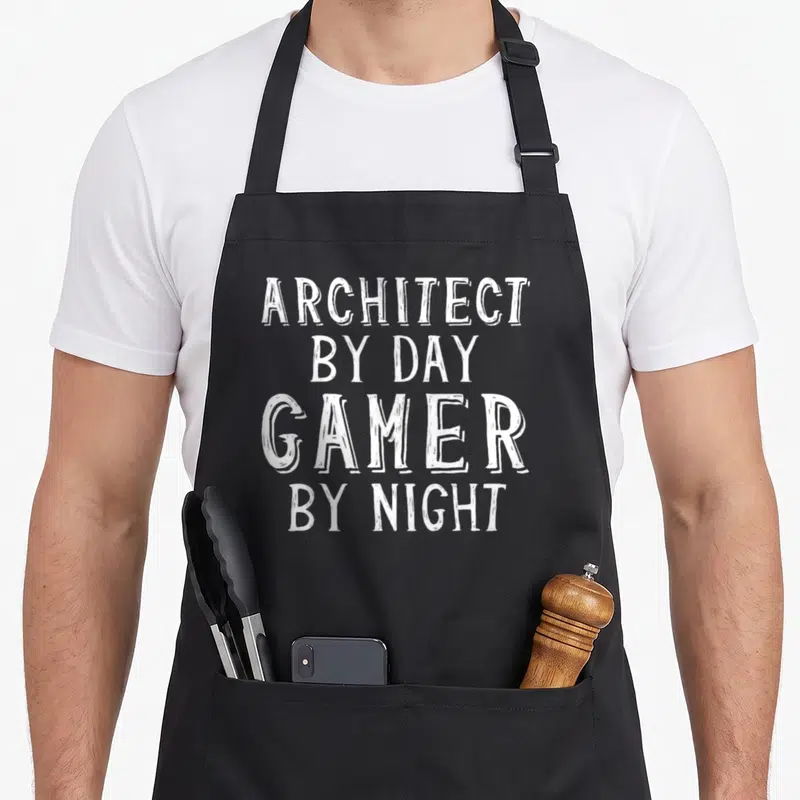 Tablier de cuisine noir avec inscription blanche « ARCHITECT BY DAY GAMER BY NIGHT » en typographie manuscrite.