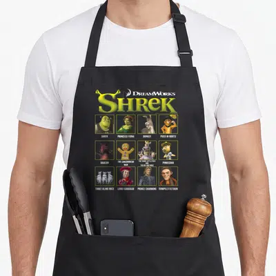Tablier de cuisine noir avec le logo Shrek et douze portraits de personnages encadrés en grille.