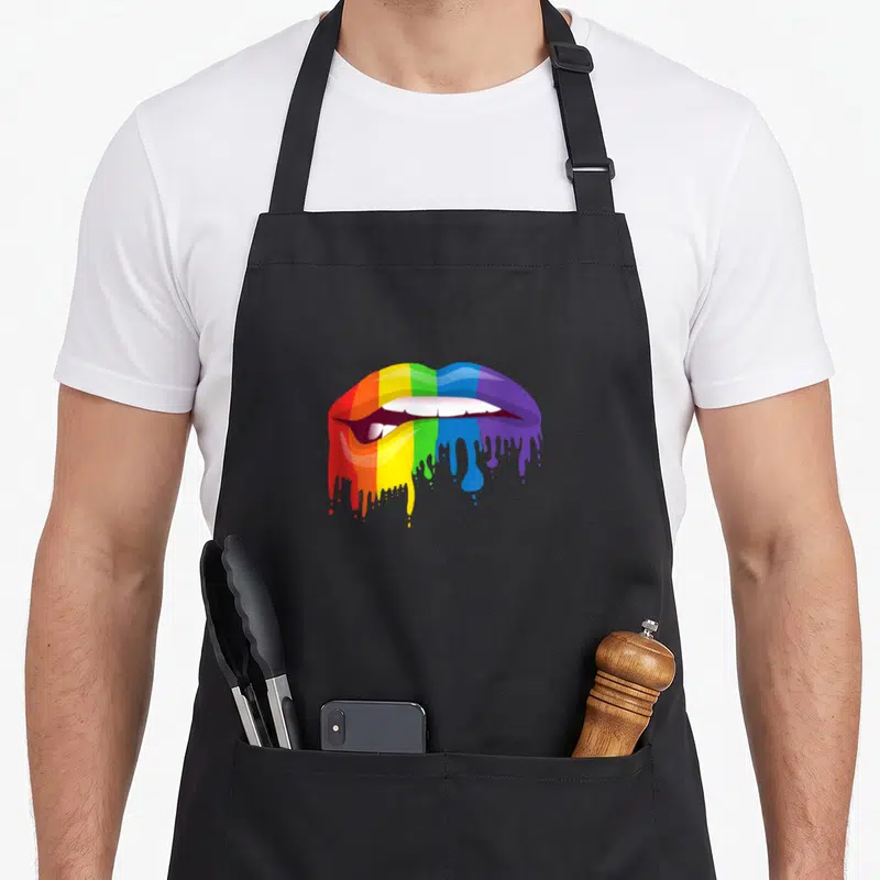 Tablier de cuisine noir avec lèvres arc-en-ciel colorées qui dégouttent sur le devant.