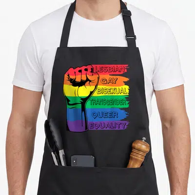 Tablier de cuisine noir avec un poing arc-en-ciel et les mots Lesbian Gay Bisexual Transgender Queer Equality imprimés en lettres capitales.