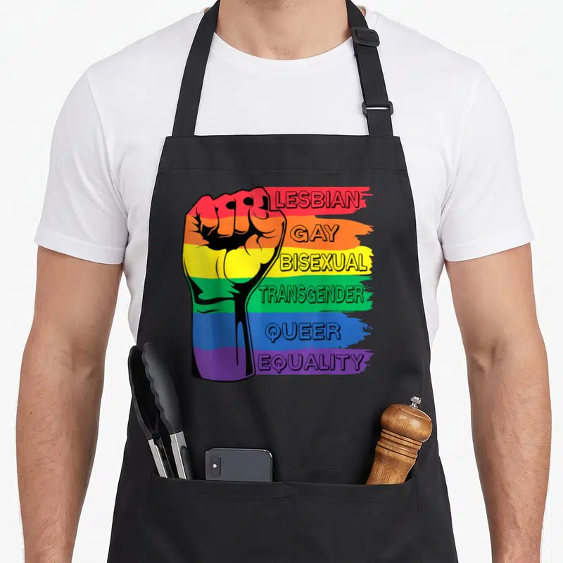 Tablier de cuisine noir avec un poing arc-en-ciel et les mots Lesbian Gay Bisexual Transgender Queer Equality imprimés en lettres capitales.