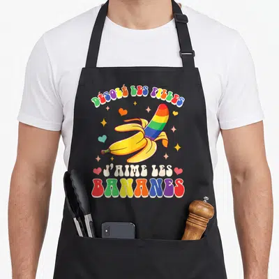 Tablier de cuisine noir avec une banane arc-en-ciel et le texte désolé les filles j'aime les bananes entouré d'étoiles et de cœurs.