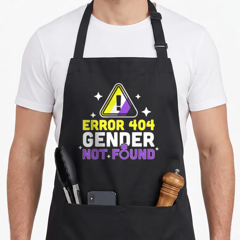 Tablier de cuisine noir avec un triangle d'avertissement coloré et le texte Error 404 Gender Not Found entouré d'étoiles.