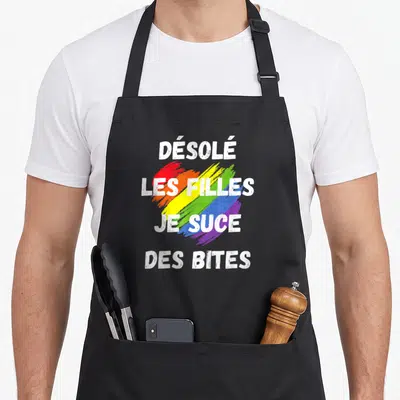 Tablier de cuisine noir avec inscription blanche et traits colorés évoquant le drapeau arc-en-ciel.