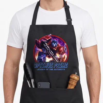 Tablier de cuisine noir avec illustration circulaire d'Optimus Prime tenant une arme sous un ciel étoilé.