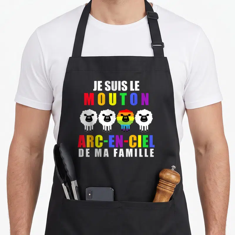 Tablier de cuisine noir avec quatre moutons dont un multicolore et le texte Je suis le mouton arc-en-ciel de ma famille.