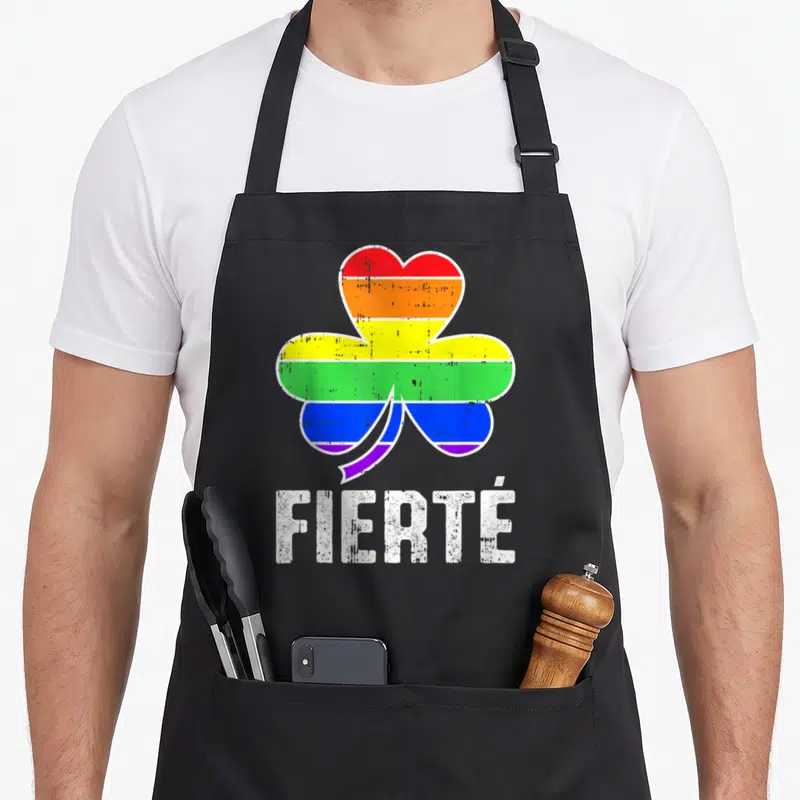Tablier de cuisine noir avec un grand trèfle multicolore et l inscription FIERTÉ en lettres blanches usées au centre.