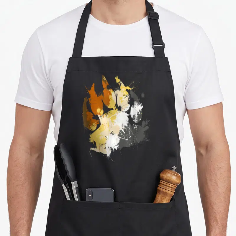 Tablier de cuisine noir avec une patte d'ours aux couleurs orange jaune blanc et gris en style éclaboussure.