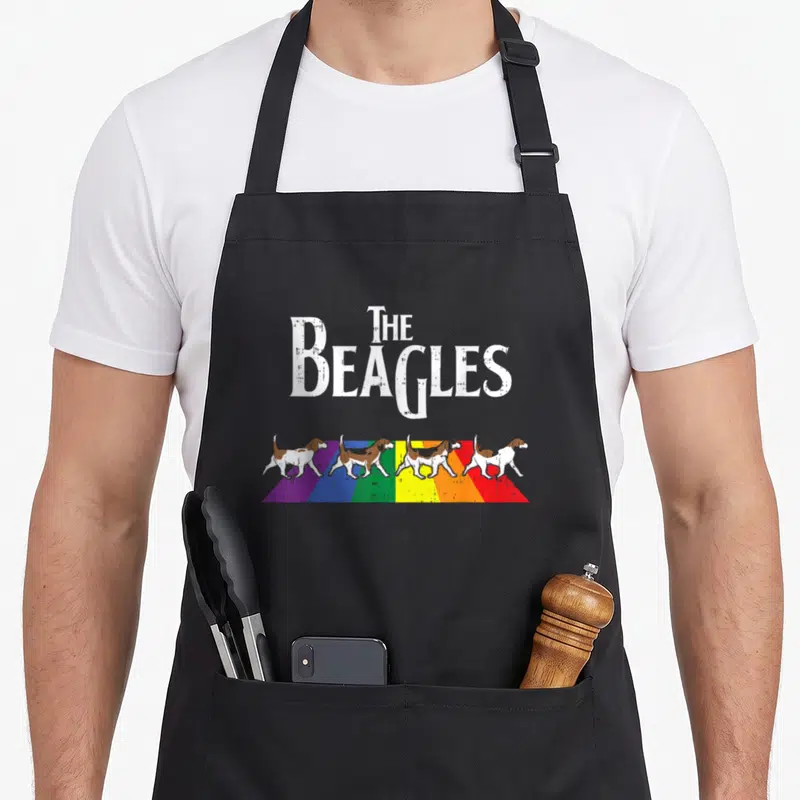 Tablier de cuisine noir avec quatre bassets sur arc-en-ciel et texte The Beagles en blanc.