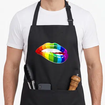 Tablier de cuisine noir avec illustration de lèvres aux couleurs de l'arc-en-ciel et des dents blanches brillantes.