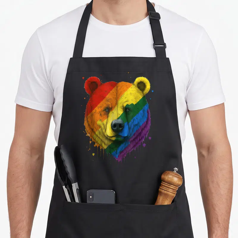 Tablier de cuisine noir avec tête d'ours aux couleurs du drapeau arc-en-ciel et effets de peinture qui coule.
