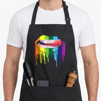Tablier de cuisine noir avec une illustration de bouche aux lèvres arc-en-ciel dont la couleur coule sur le côté droit.