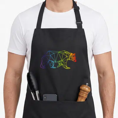 Tablier de cuisine noir avec un ours géométrique multicolore formant un arc-en-ciel stylisé sur le devant.