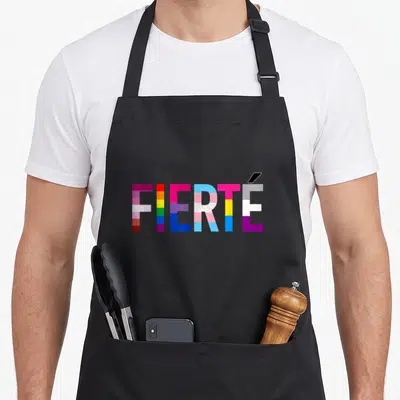 Tablier de cuisine noir avec le mot Fierté stylisé en blocs multicolores représentant l'arc-en-ciel.