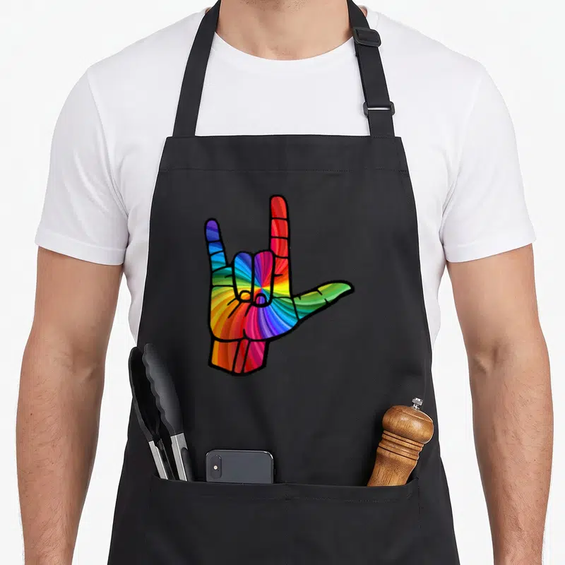 Tablier de cuisine noir avec une main aux couleurs de l'arc-en-ciel formant un signe gestuel stylisé.