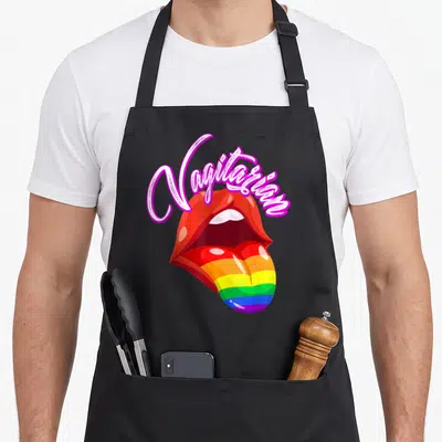 Tablier de cuisine noir avec illustration de lèvres rouges et langue aux couleurs de l'arc-en-ciel sous une inscription rose.