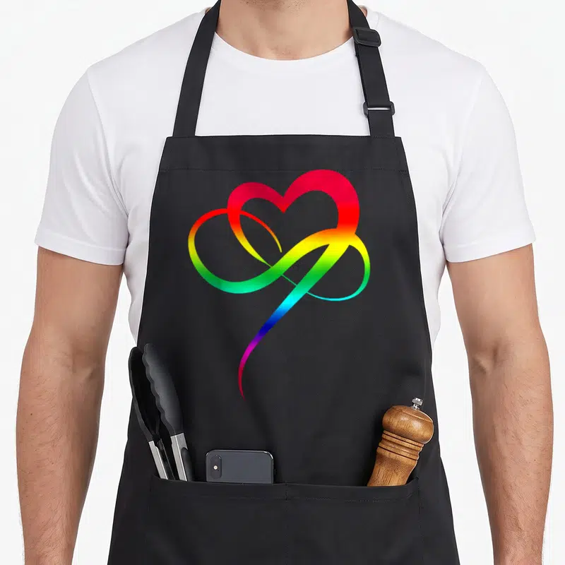 Tablier de cuisine noir avec un cœur arc-en-ciel stylisé en forme de boucle infinie.