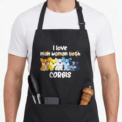 Tablier de cuisine noir avec cinq corgis colorés et texte blanc barré en anglais.