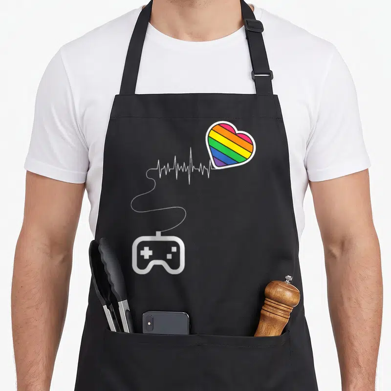 Tablier de cuisine noir avec un cœur arc-en-ciel relié à un contrôleur de jeu via une ligne de rythme cardiaque blanche.