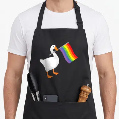Tablier de cuisine noir avec une oie blanche tenant un drapeau arc-en-ciel multicolore dans son bec.