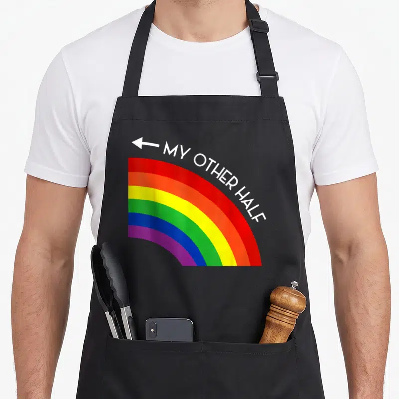 Tablier de cuisine noir avec un arc-en-ciel coloré et une flèche blanche pointant vers le texte My Other Half.