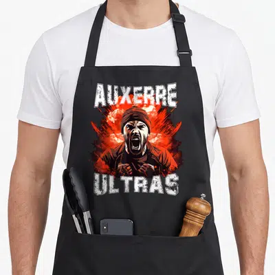Tablier de cuisine noir avec illustration d'un supporterAuxerre Ultras criant sur fond rouge et texte blanc.