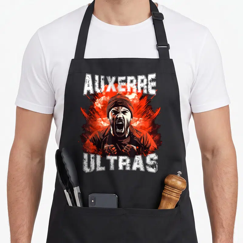 Tablier de cuisine noir avec illustration d'un supporterAuxerre Ultras criant sur fond rouge et texte blanc.