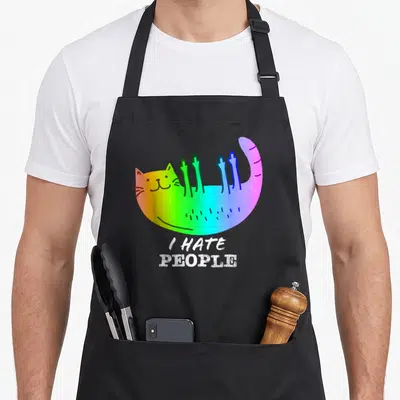 Tablier de cuisine noir avec un chat arc-en-ciel levant les pattes et le texte « Je déteste les gens » en blanc.