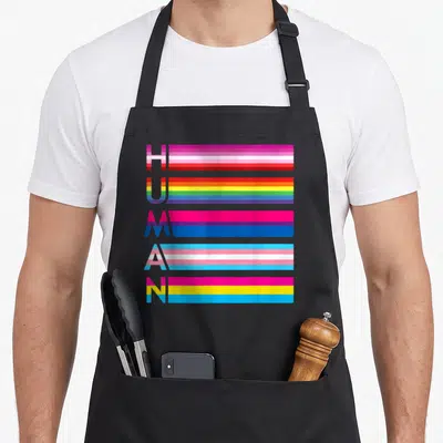 Tablier de cuisine noir avec le mot humain formé par des drapeaux multicolores horizontaux.