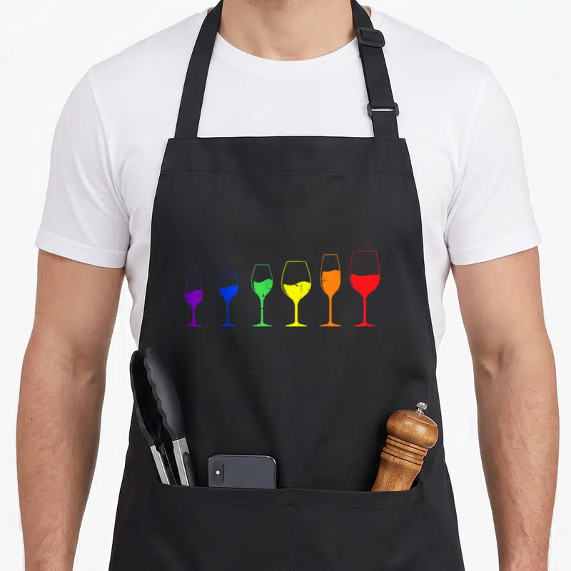Tablier de cuisine noir avec six verres à vin colorés en arc-en-ciel disposés en ligne.