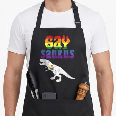 Tablier de cuisine noir avec un dinosaure blanc et un cœur arc-en-ciel imprimé sur le devant.