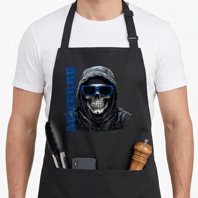 Tablier de cuisine noir avec un crâne en capuche portant des lunettes bleues et le mot Auxerre imprimé verticalement.