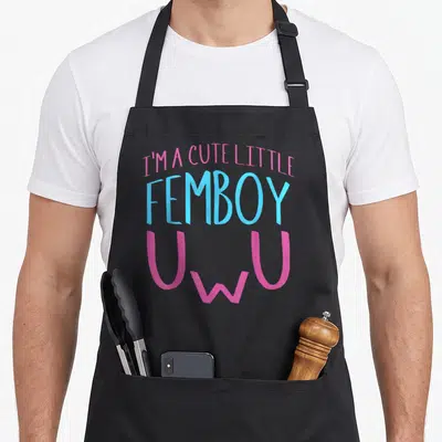 Tablier de cuisine noir avec le texte J'suis un petit femboy mignon UwU en rose et bleu ciel.