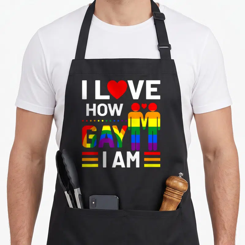 Tablier de cuisine noir avec le texte J'aime à quel point je suis gay et deux silhouettes arc-en-ciel tenant la main.