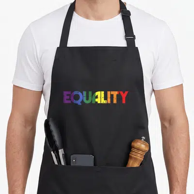 Tablier de cuisine noir avec le mot Equality écrit en lettres colorées arc-en-ciel au centre.