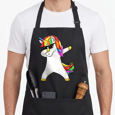 Tablier de cuisine noir avec licorne blanche effectuant un dab, portant des lunettes de soleil et une crinière arc-en-ciel.
