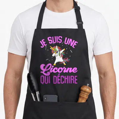 Tablier de cuisine noir avec une licorne blanche en train de faire un dab et du texte rose vif.
